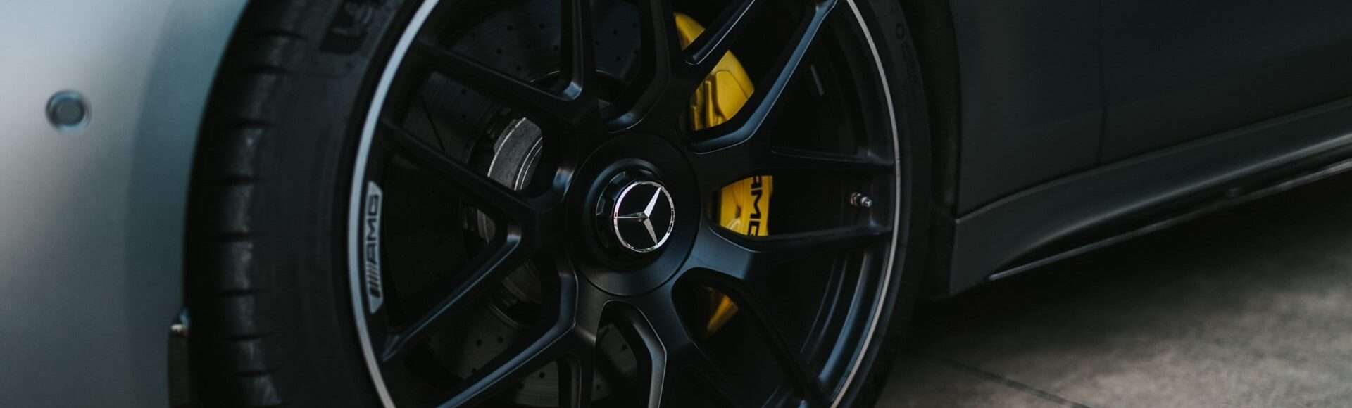 Close-up of a Mercedes-AMG wheel with yellow brake calipers and drilled brake discs.