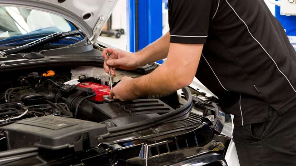 A qualified Cox Auto technician performing an engine diagnostic under the hood of a European vehicle.