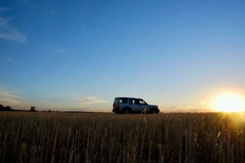 Car stopped beside a field.