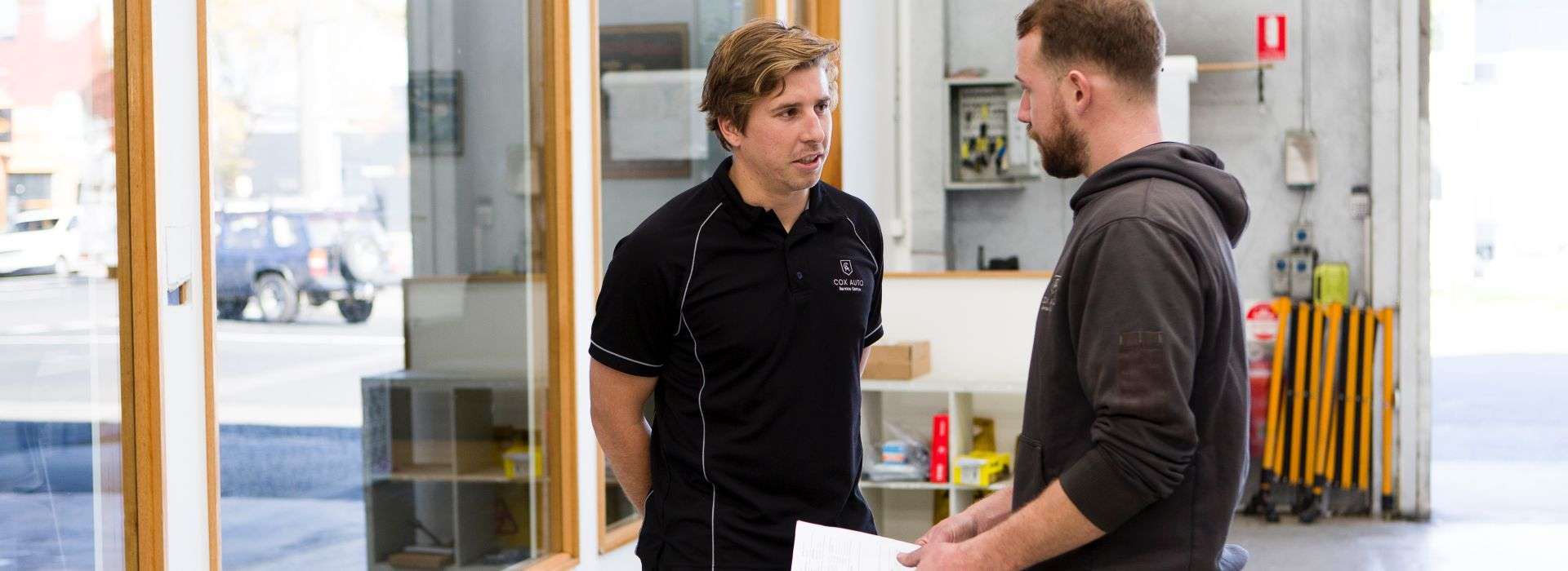 Our our South Melbourne garage, a Cox Auto mechanic chats to a client about a pre-purchase inspection report.