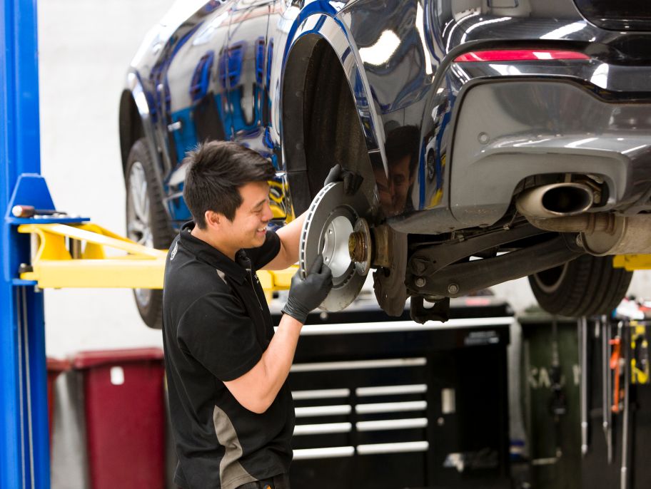 Mechanic installing a disc on a car lifted in a workshop.