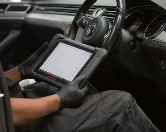 A close-up of a Cox Auto mechanic review notes while servicing a car.