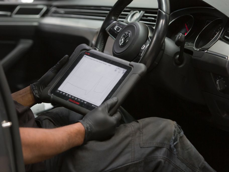 A close-up of a Cox Auto mechanic review notes while servicing a car.