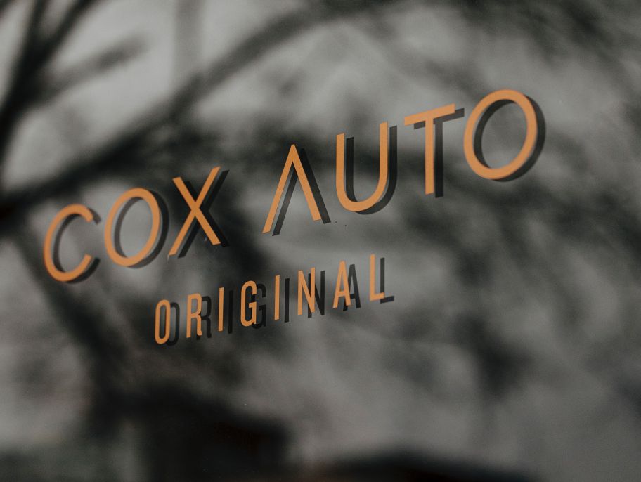Cox Auto logo displayed on a reflective glass surface.