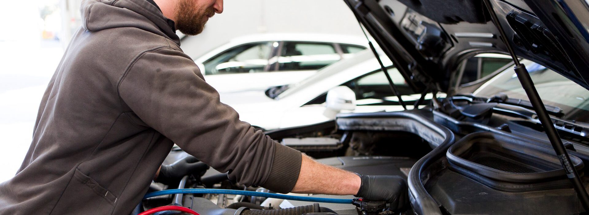 A qualified Cox Auto technician performing an engine diagnostic under the hood of a European vehicle.