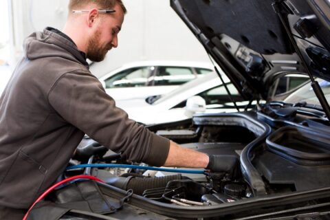 A qualified Cox Auto technician performing an engine diagnostic under the hood of a European vehicle.