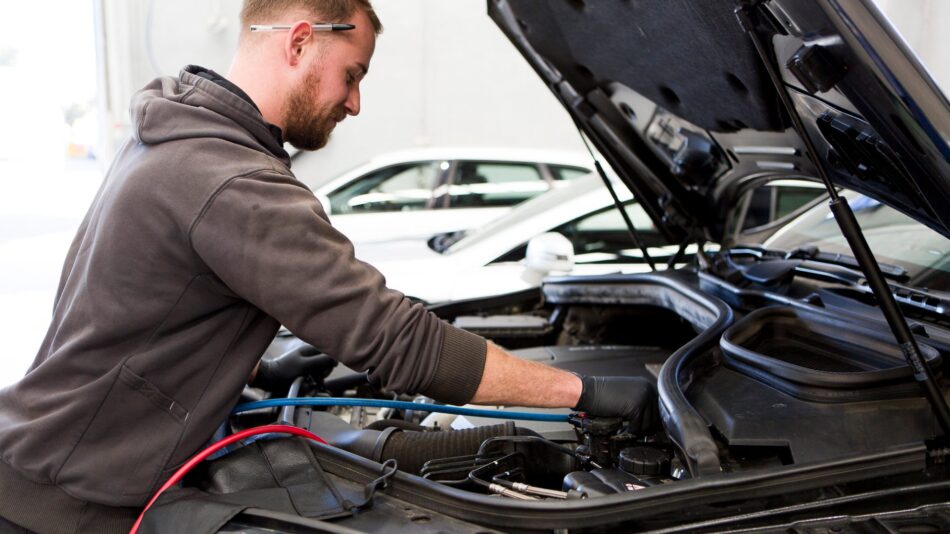 A qualified Cox Auto technician performing an engine diagnostic under the hood of a European vehicle.