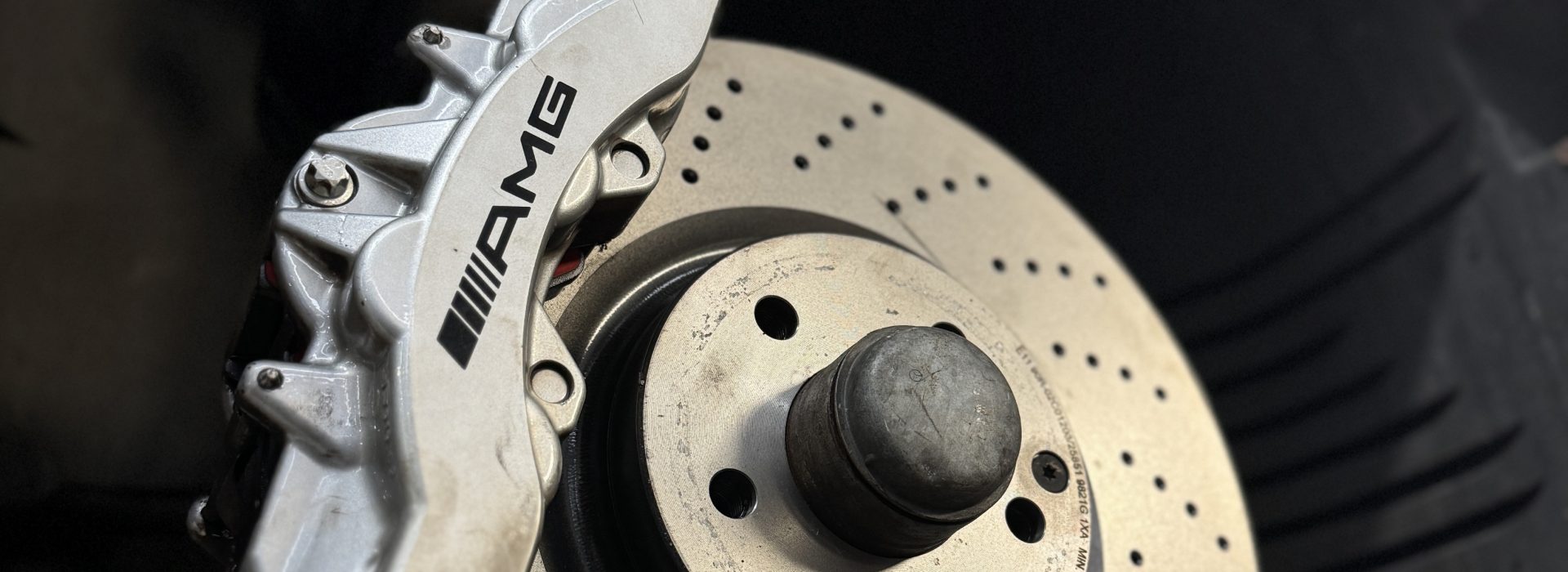 Close-up of an AMG-branded brake caliper and perforated brake disc.