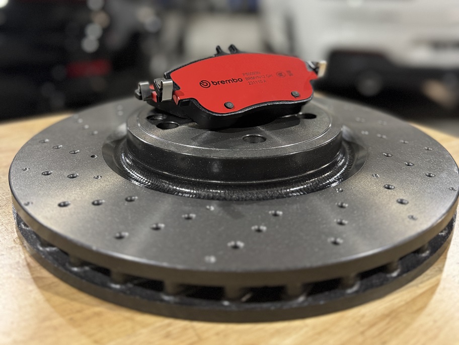 Brembo red brake pad resting on a drilled brake disc.