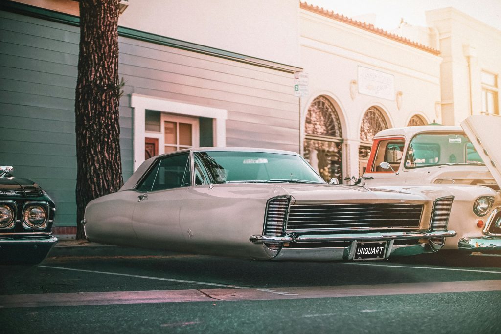 A classic car is parked on the street, apparently floating. A tongue-in-cheek suggestion of retro-futurism.