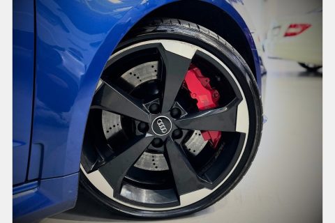 Close-up of a wheel with red brake calipers and drilled brake discs.