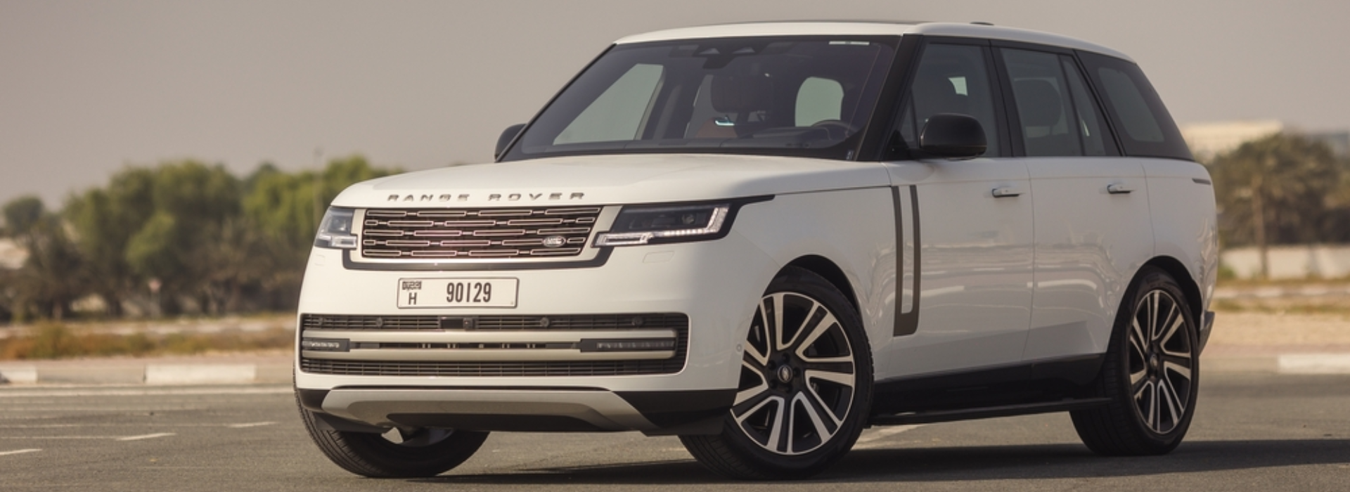 Modern white Range Rover SUV parked outdoors on a clean, open road under clear skies.