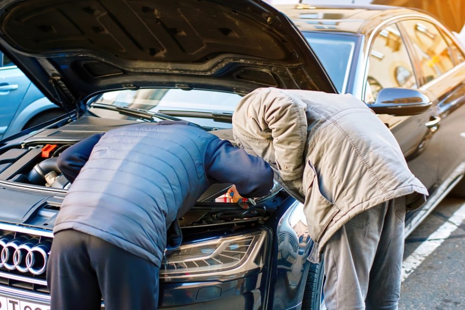 Two men inspecting Audi car, attention to detail in car buying process. Used car seller and buyer engage in detailed check under the hood.