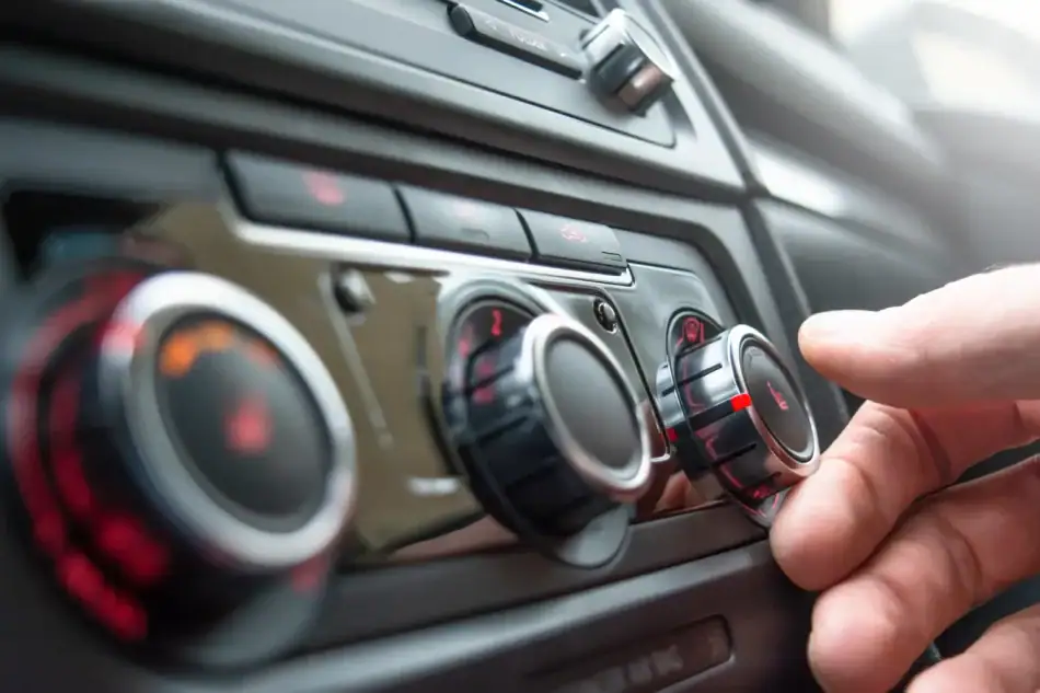 Hand adjusting a car air conditioning control knob on the dashboard.