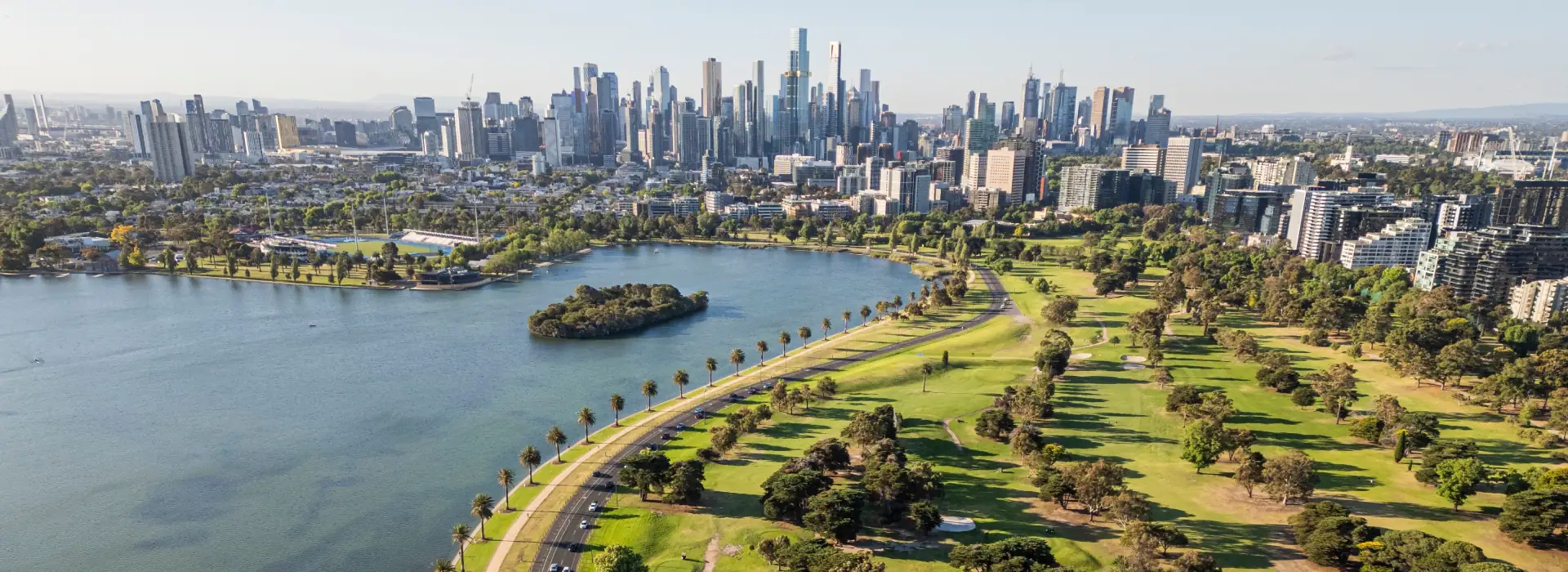 Scenic aerial view of Melbourne's skyline and Albert Park Lake showcasing the city's vibrant urban landscape and lush green spaces.