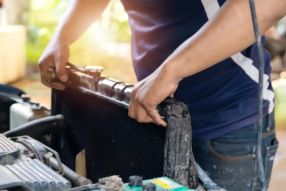 Mechanic installing or removing a car radiator under the hood.
