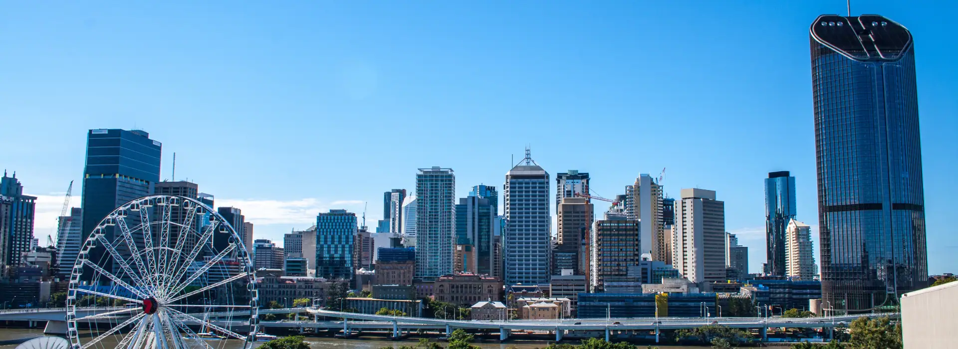 Modern Sydney city skyline with high-rise buildings and the Sydney Harbour Ferris wheel on a clear, sunny day.